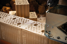 Auftrag mit der Mörtelrolle: Das Aufbringen des Lehmdünnbettmörtels von ClayTec funktioniert analog zum Mauern mit konventionellen Baustoffen. Foto: Bauhaus Filmwerkstatt